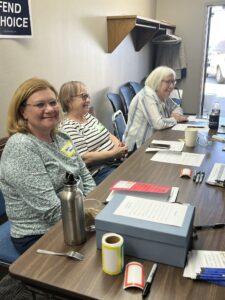 Assistants and Attendees. Board member Susan Stoefen (left) and local Democrats Lucinda Hoskins (middle) and Julie Lawrence (right) helped with setup, signing in attendees, and making sure everything was running smoothly.